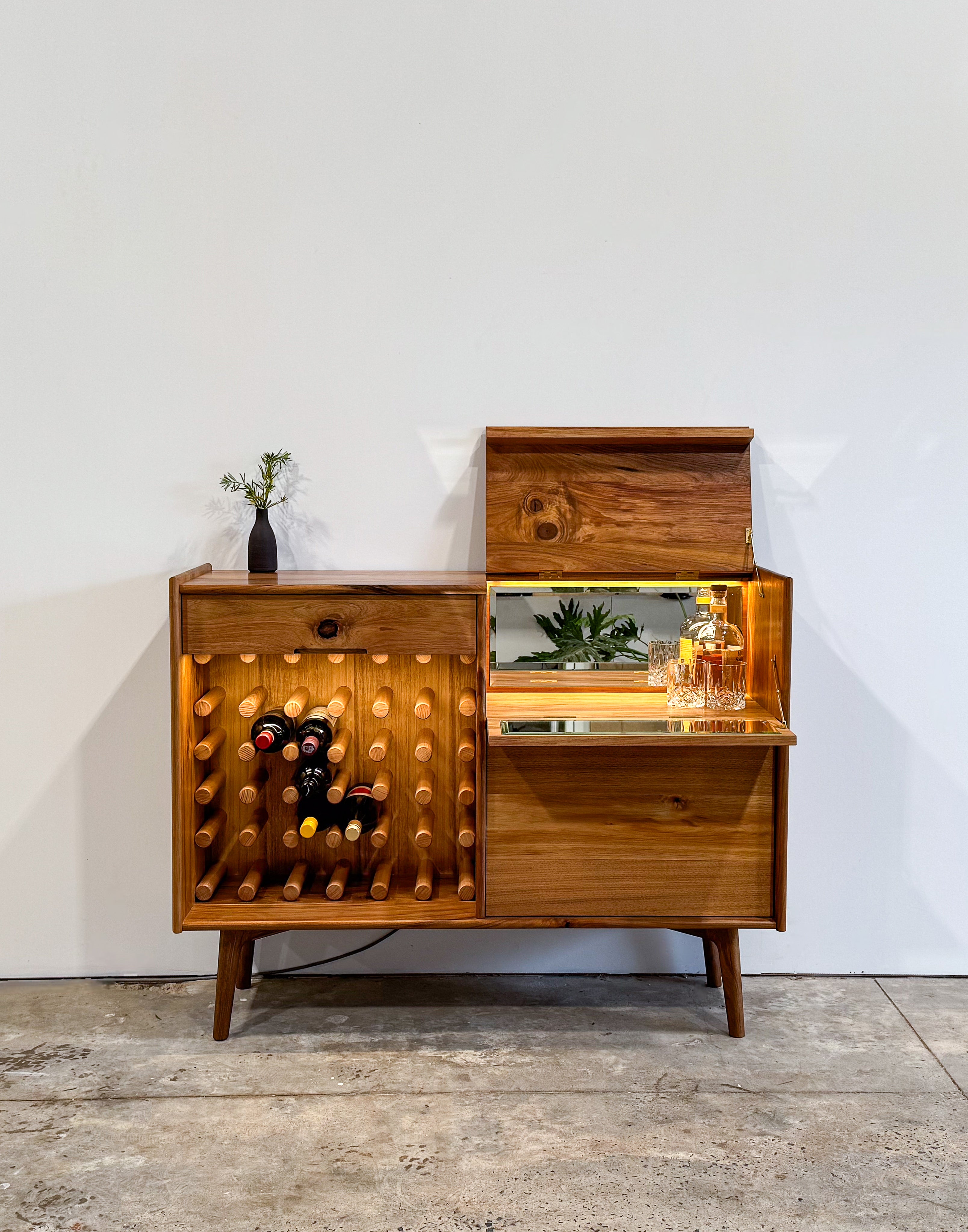 Dark brown timber drinks cabinet with wine rack, LED lighting, brass hinges and mirror inlay cocktail hatch and drawer. Handmade in Melbourne Australia from Tasmanian Blackwood